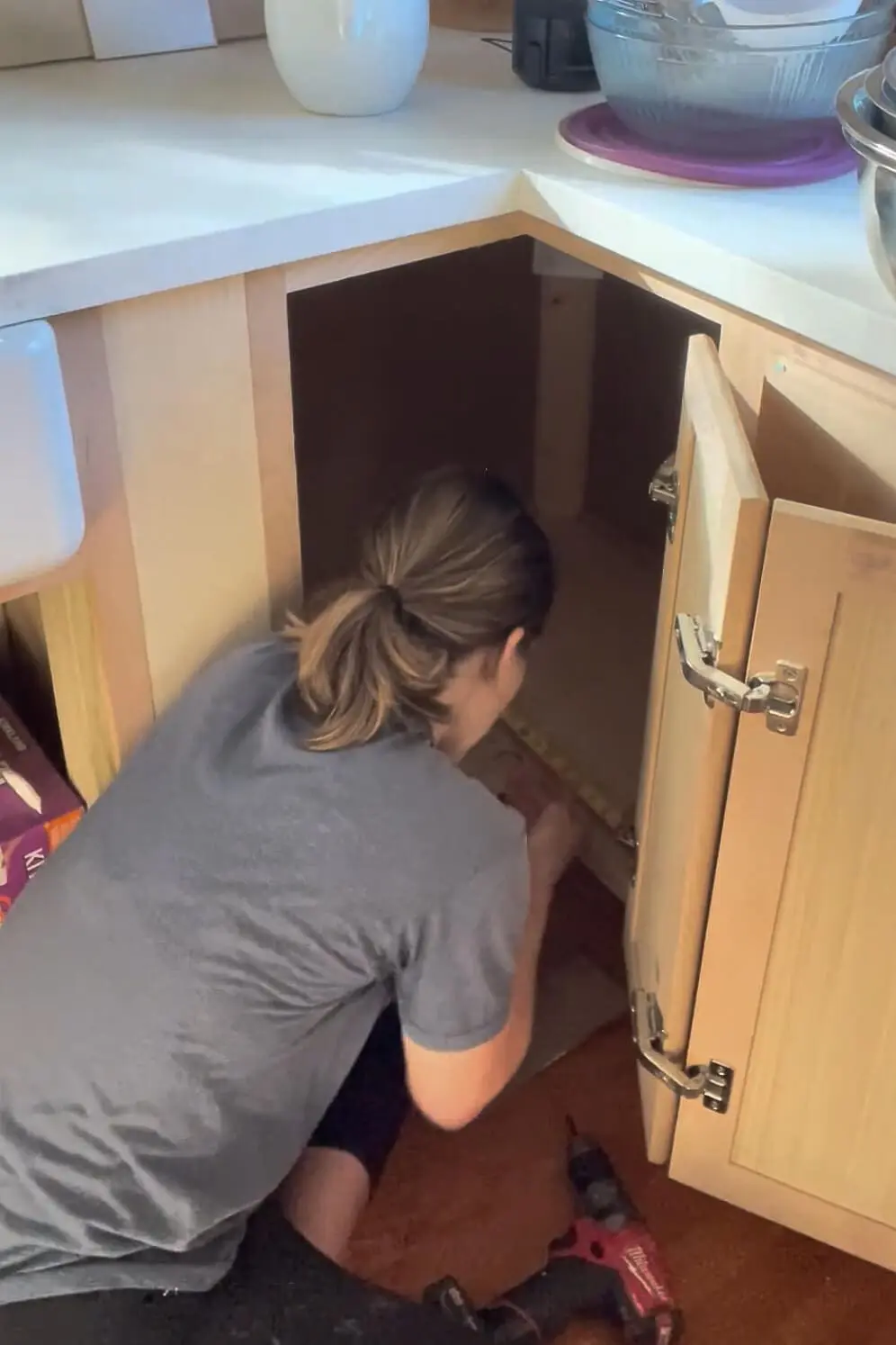 Measuring in order to add a shelf to a kitchen cabinet.